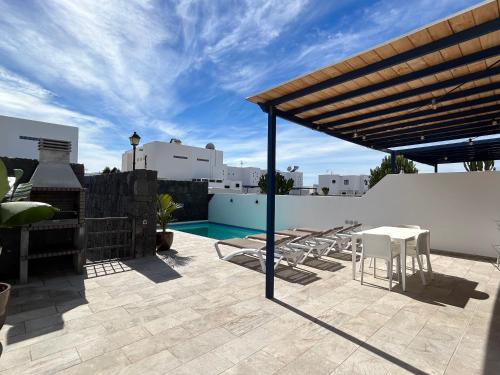 a patio with a table and chairs and a swimming pool at Casa Oona in Playa Blanca