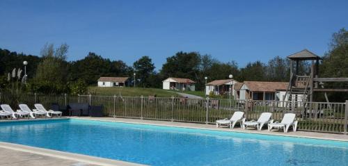 a swimming pool with chairs and a fence at Le pivert in Orist