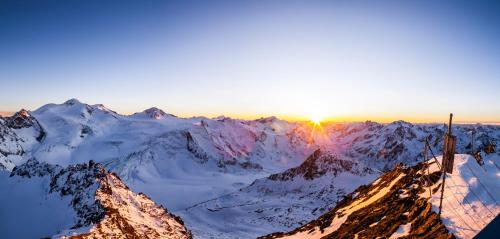 a sun setting over a snow covered mountain at Apart Alpenzeit in Arzl im Pitztal