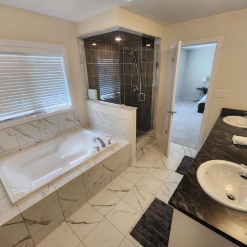 ein Bad mit einer Badewanne, einer Dusche und einem Waschbecken in der Unterkunft New Niagara Retreat - Entire Home, 15 min drive to Falls, Sleeps 9, 4BDR in Thorold