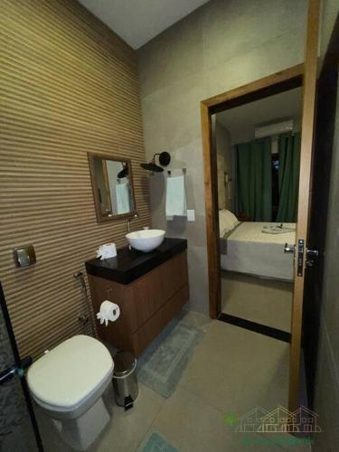 a bathroom with a toilet and a sink and a mirror at Residencial Buritis-Tarumã Hípica Park in Bonito