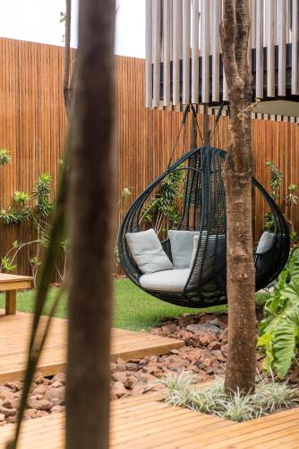a hammock in a garden with a tree at Pousada Maria Flor in Fernando de Noronha