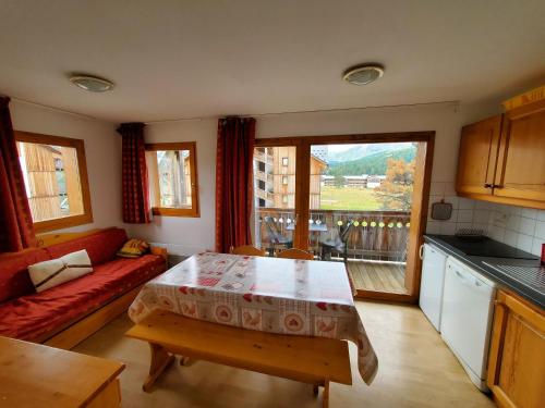 a kitchen and living room with a table and a couch at ANCOLIE 23 Les Chalets de Super D in Le Dévoluy