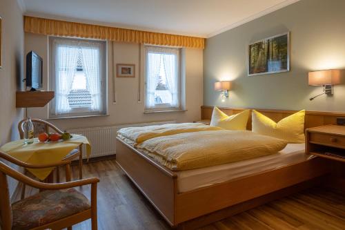 a bedroom with a bed and a desk and two windows at Landhotel Gasthof zur Post in Winterberg