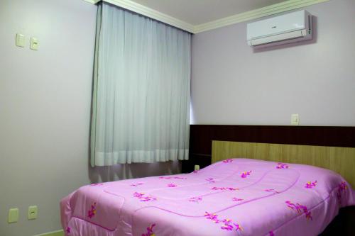 a bedroom with a pink bed with pink sheets at Tranquilidade na Morada do Sol in Piratuba