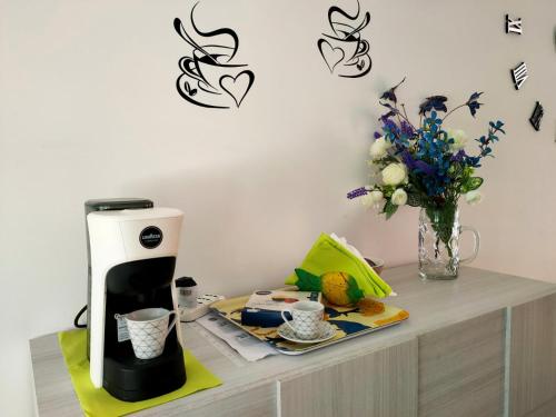 a coffee maker on a table with a vase of flowers at Villino Maria Pia, appartamento in villino in centro storico L'Aquila in LʼAquila