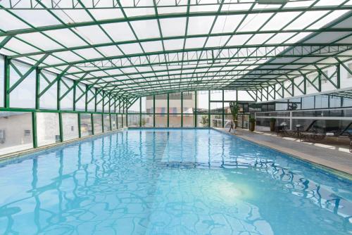 an indoor swimming pool with a glass ceiling at Faro Hotel Atibaia in Atibaia
