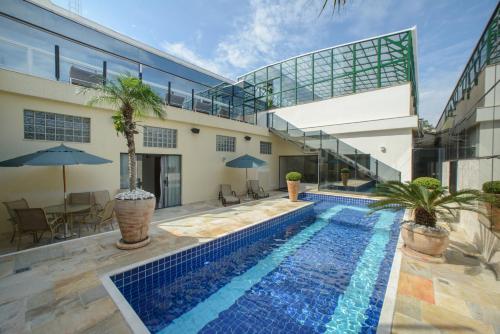 a house with a swimming pool in front of a building at Faro Hotel Atibaia in Atibaia