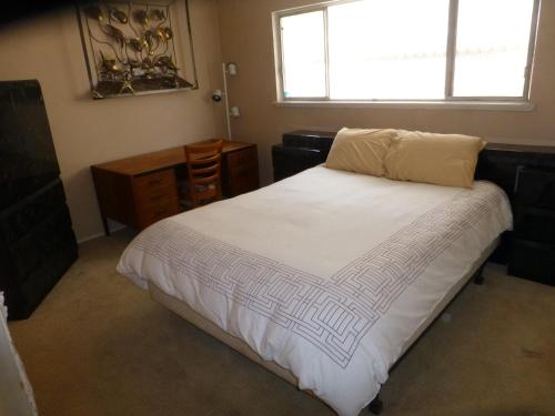 1 dormitorio con 1 cama blanca grande y ventana en Nice Northridge 4-2-2 Pool home near CSUN and Pierce College, en Northridge
