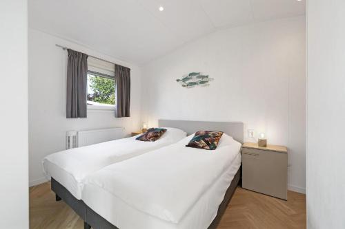 twee bedden in een kamer met witte muren bij Chalet De strandgaper - Ouddorp - Not for companies in Ouddorp