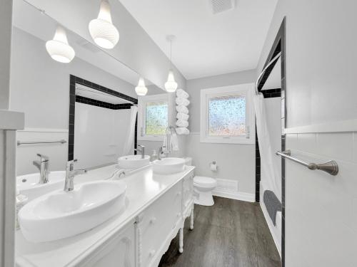 a white bathroom with two sinks and a toilet at Park Bungalow - Seacliff Beach Suites in Leamington