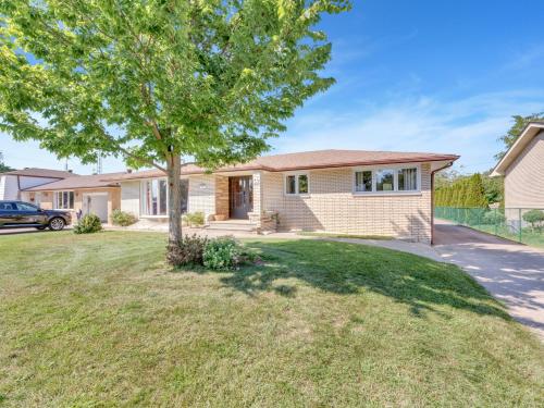 a house with a tree in a yard at Park Bungalow #4 - Seacliff Beach Suites in Leamington