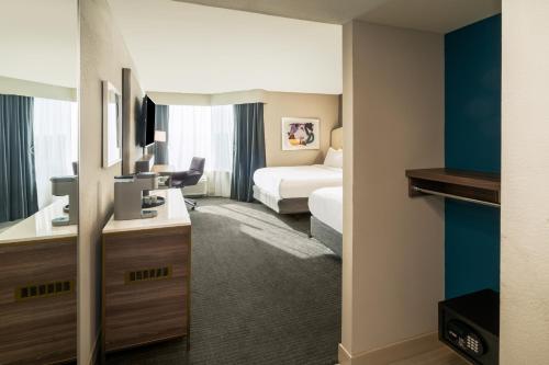 a hotel room with a bedroom with a bed and a mirror at Crowne Plaza Atlanta NE - Norcross in Norcross