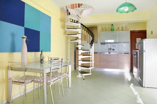 a dining room with a glass table and a spiral staircase at Adriana casa vacanze mare Etna Sicilia in Acireale