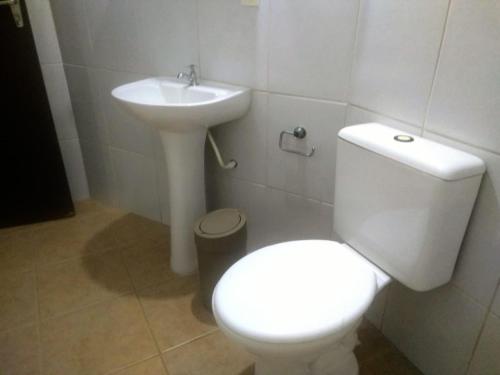 a bathroom with a white toilet and a sink at quarto 03 triplo econômico bwc exclusivo corredor in Penha