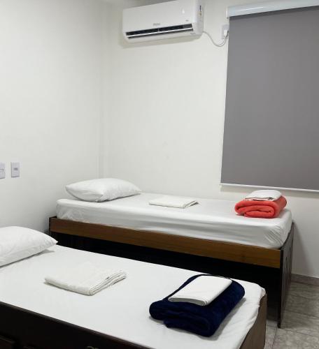 two beds in a dorm room with a red shirt on them at Apartamento em Uberlândia - Apê do Pedro in Uberlândia