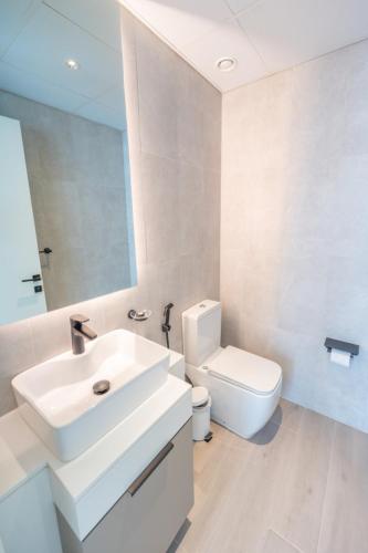 a white bathroom with a sink and a toilet at Midtown Haven Cozy One Bed in Dubai in Dubai