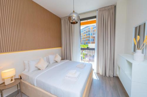 a bedroom with a white bed with a window at Midtown Haven Cozy One Bed in Dubai in Dubai