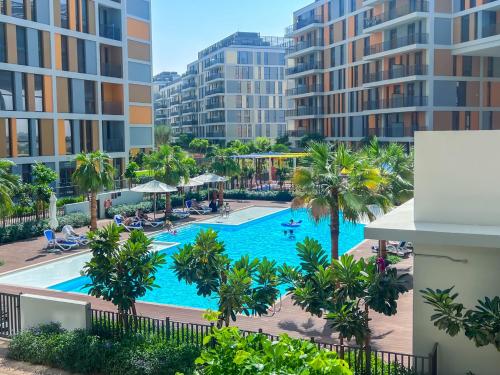 an aerial view of a pool with palm trees and buildings at Midtown Haven Cozy One Bed in Dubai in Dubai