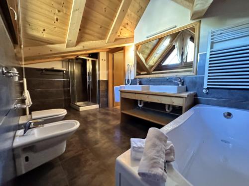 a bathroom with a tub and a toilet and a sink at Hotel Betulla in Madonna di Campiglio