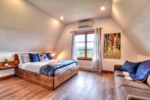 Un dormitorio con una cama y un sofá y una ventana. en Plateau A - Mont-Tremblant, en Mont-Tremblant