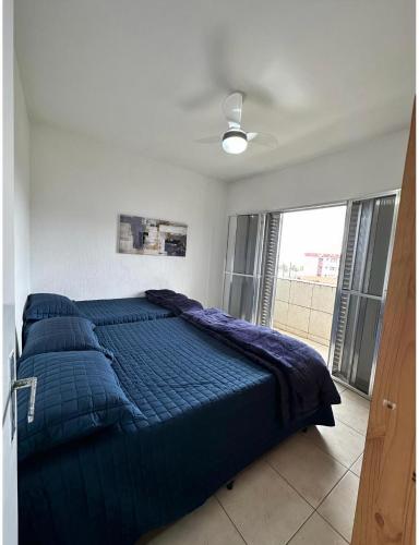 a bed with a blue comforter in a bedroom at AP Aconchegante a 60 Metros da Praia, vista mar 302 in Praia Grande
