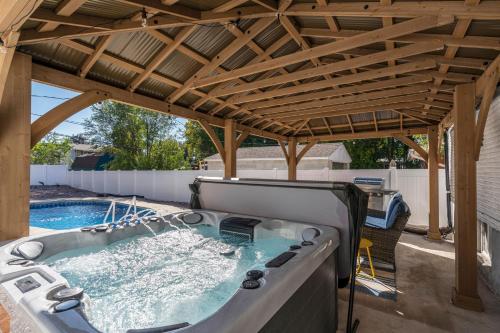 a hot tub under a pergola next to a pool at Charming Salt Lake City Home Minutes from Airport, Downtown SLC , Skiing in South Salt Lake
