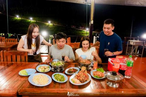 a group of people sitting around a table eating food at เดอะวอเตอร์ปาร์ครีสอร์ท- The Water Park Resort in Ban Laem Mong Khoi