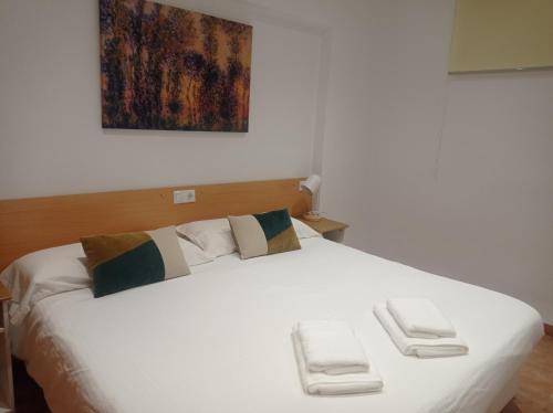 a white bed with two towels on top of it at Beach Nice Flat in Puebla de Farnals