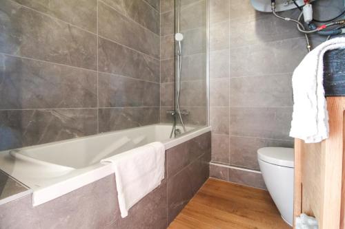 a bathroom with a tub and a toilet at Stunning 4-bedroom apartment Flaine Foret, fully refurbished, beautiful panoramic views in Flaine