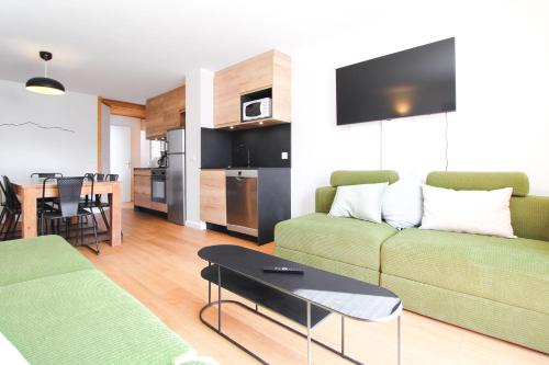 a living room with a green couch and a table at Stunning 4-bedroom apartment Flaine Foret, fully refurbished, beautiful panoramic views in Flaine