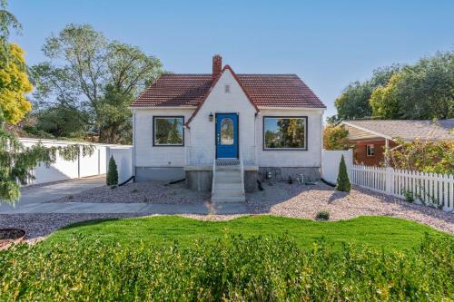 a white house with a blue door in a yard at Charming Salt Lake City Home Minutes from Airport, Downtown SLC , Skiing in South Salt Lake