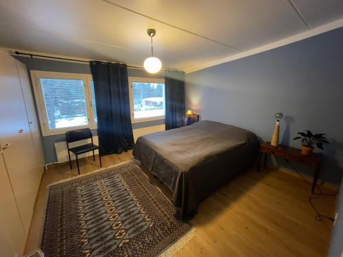 a bedroom with a bed and a chair and two windows at Spacious city apartment in Rovaniemi