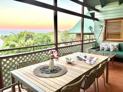 a wooden table with a vase of flowers on a balcony at Loloma! Luxe 4 bed, 2 bath Villa in Yamba