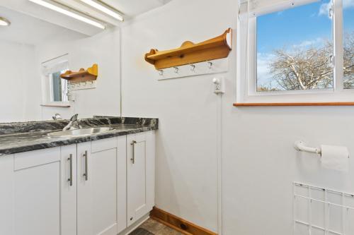 a white kitchen with a sink and a window at Semi Detached Mountain View Chalet in Blue Mountains