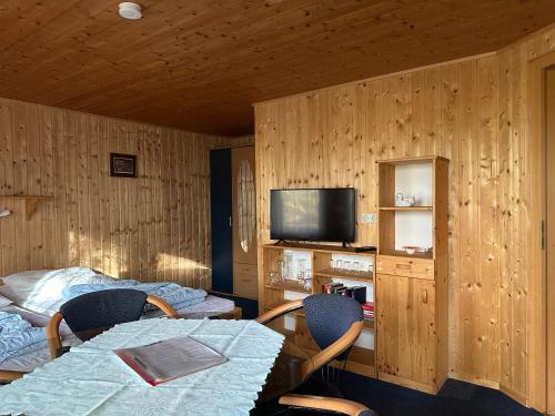 a room with a table and chairs and a television at Feriendorf Kimbucht in Reichendorf