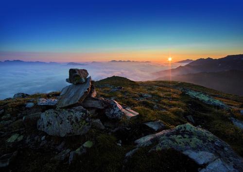 a cross sitting on top of a mountain at sunset at Apart Alpenzeit in Arzl im Pitztal