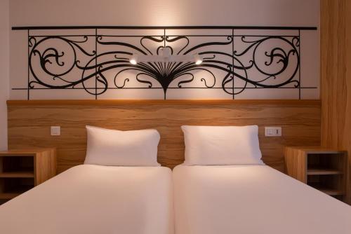two white beds in a bedroom with a headboard at Au Pacific Hotel in Paris