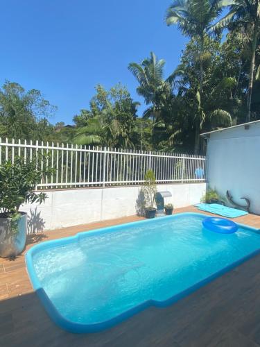 a swimming pool in a backyard with a white fence at Tia Moni - diárias individuais in Blumenau