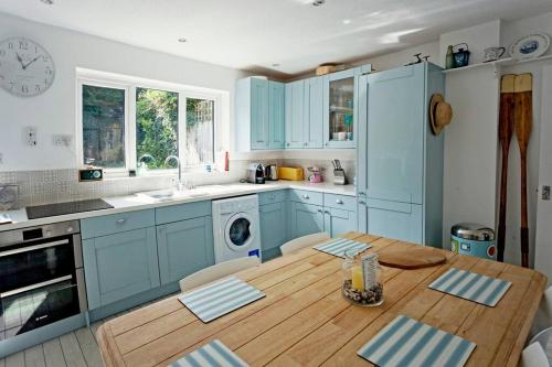 uma cozinha com armários azuis e uma mesa de madeira em A Seafood and Walking Enthusiasts Quiet Escape. em West Mersea