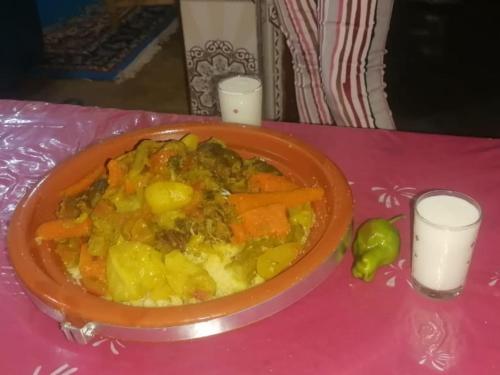 a bowl of food on a pink table with two candles at Bivouac Liguera chez Ahmed in Mhamid