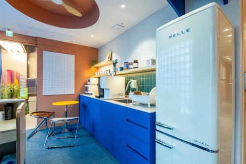 una cucina con armadi blu e uno sgabello giallo di Hithere City Myeongdong a Seul
