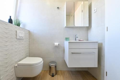 a white bathroom with a toilet and a sink at Boutique Hotel IVY'Z in Novalja