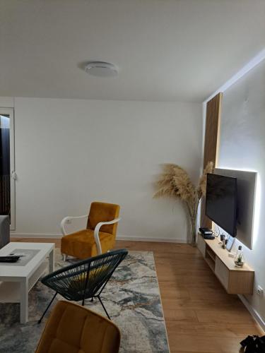 un soggiorno con TV, divano e sedie di Apartman Neyla a Mostar