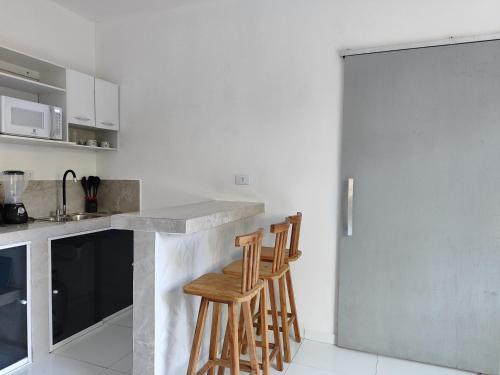 a kitchen with a counter with two stools at a bar at Apartamento Inteligente in Japaratinga