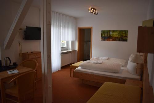 a bedroom with a bed and a table and a television at Hotel Talblick in Dobel