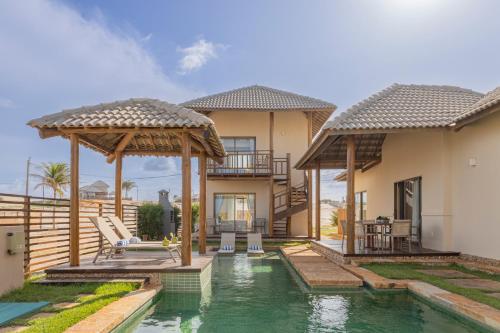 a villa with a swimming pool and a house at The Coral Beach Resort by Atlantica in Flecheiras