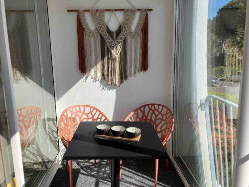 uma mesa preta numa varanda com duas chávenas em Étoile de Mer * wifi * Parking * Clim * Central * em La Grande-Motte