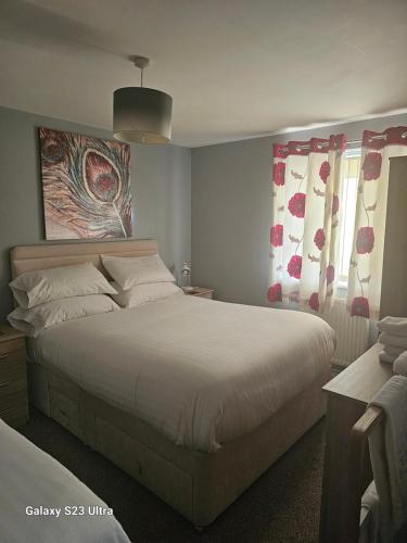 a bedroom with a large white bed with red curtains at A Home From Home 3 in Plymouth