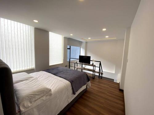 1 dormitorio con 1 cama y escritorio con TV en Hermoso Apartaestudio Duplex cerca a Unicentro en Pasto